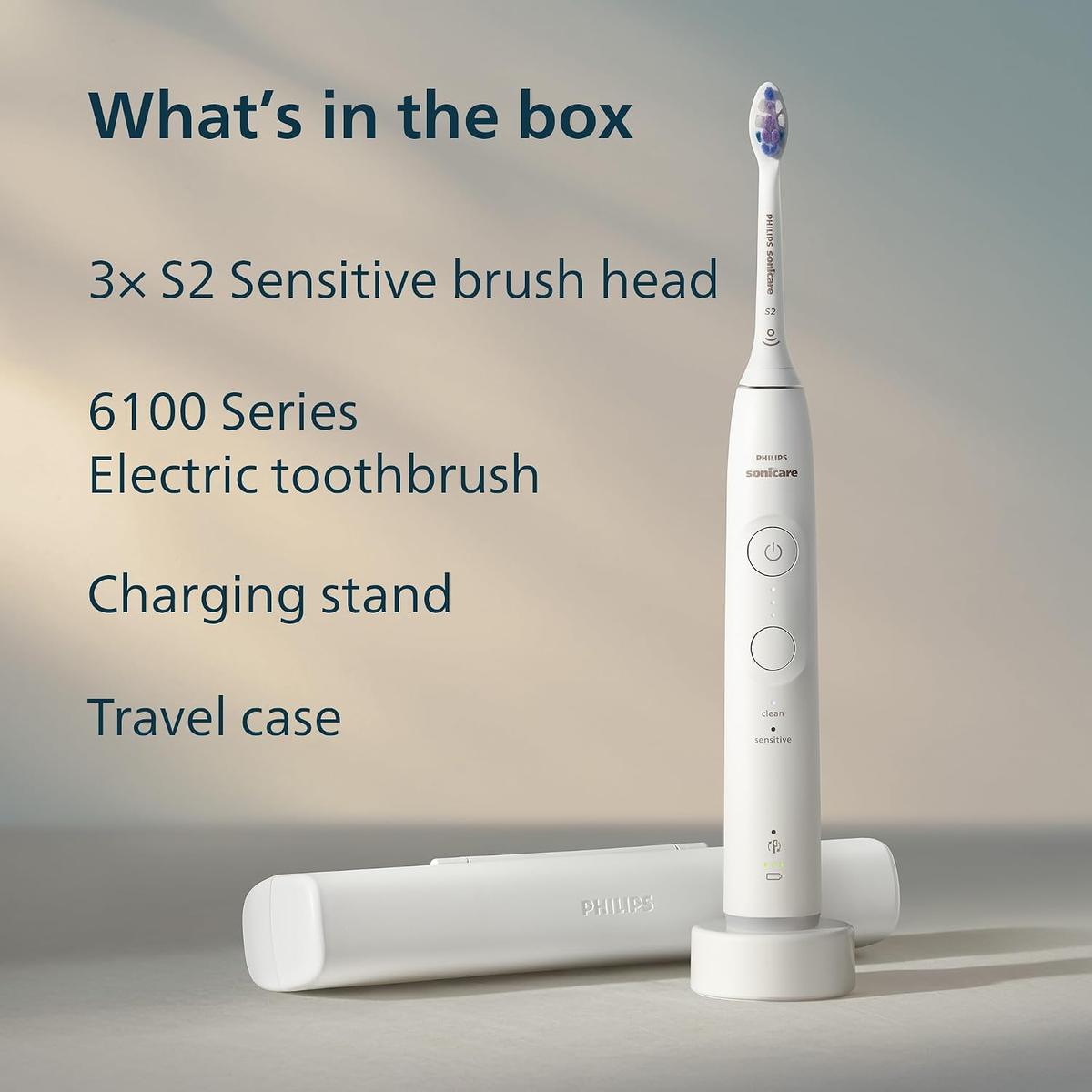 White Philips Sonicare 6100 electric toothbrush with S2 brush head, charging base, and travel case on a neutral background.