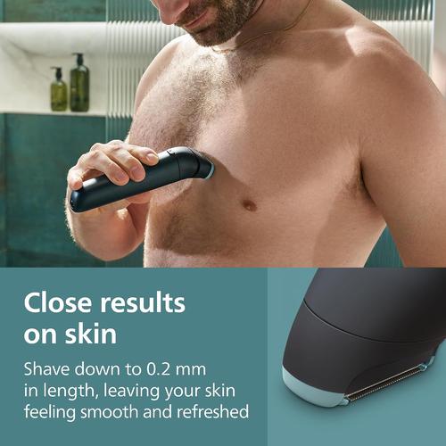 Man using a black Philips body groomer on his chest, featuring a close-up of the replacement foil head with a protective guard.