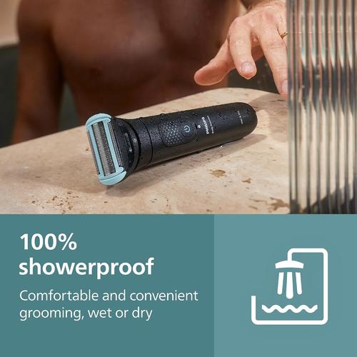 Black Philips body groomer with a light blue foil head resting on a wet surface, highlighting its showerproof design.