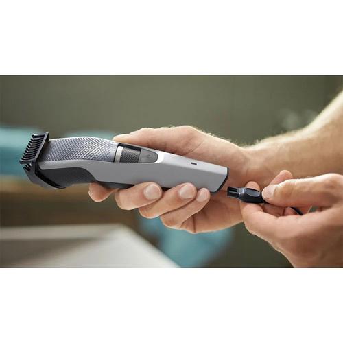 Grey Philips Series 3000 beard trimmer with a precision dial being charged with a USB cable in a hand.